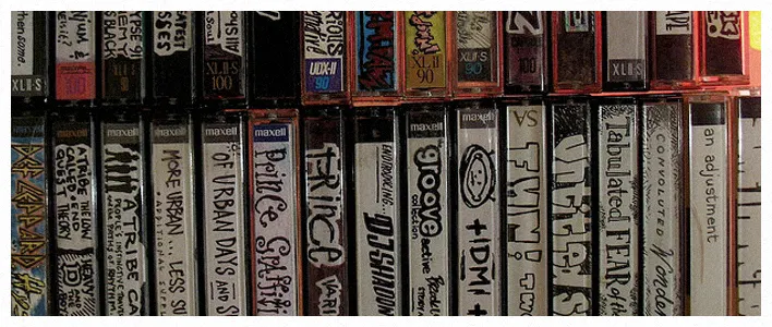 A tightly packed row of cassette tapes with hand-labeled spines, including Maxell and XLII cases.