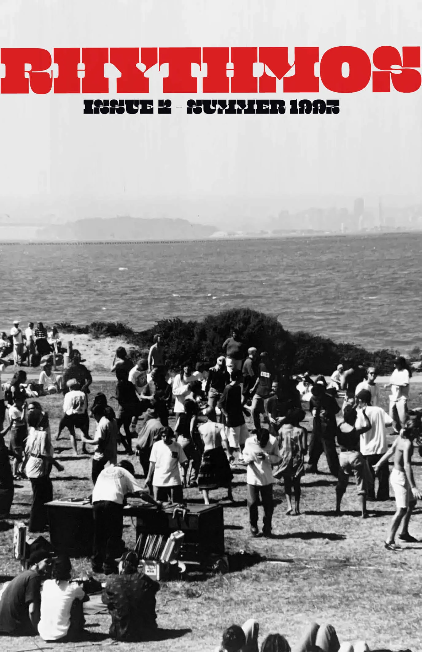 Zine cover reading "Rhythmos, Issue 2 – Summer 1993" over a black-and-white photo of a crowd dancing on a grassy hillside beside a bay with a distant city skyline.