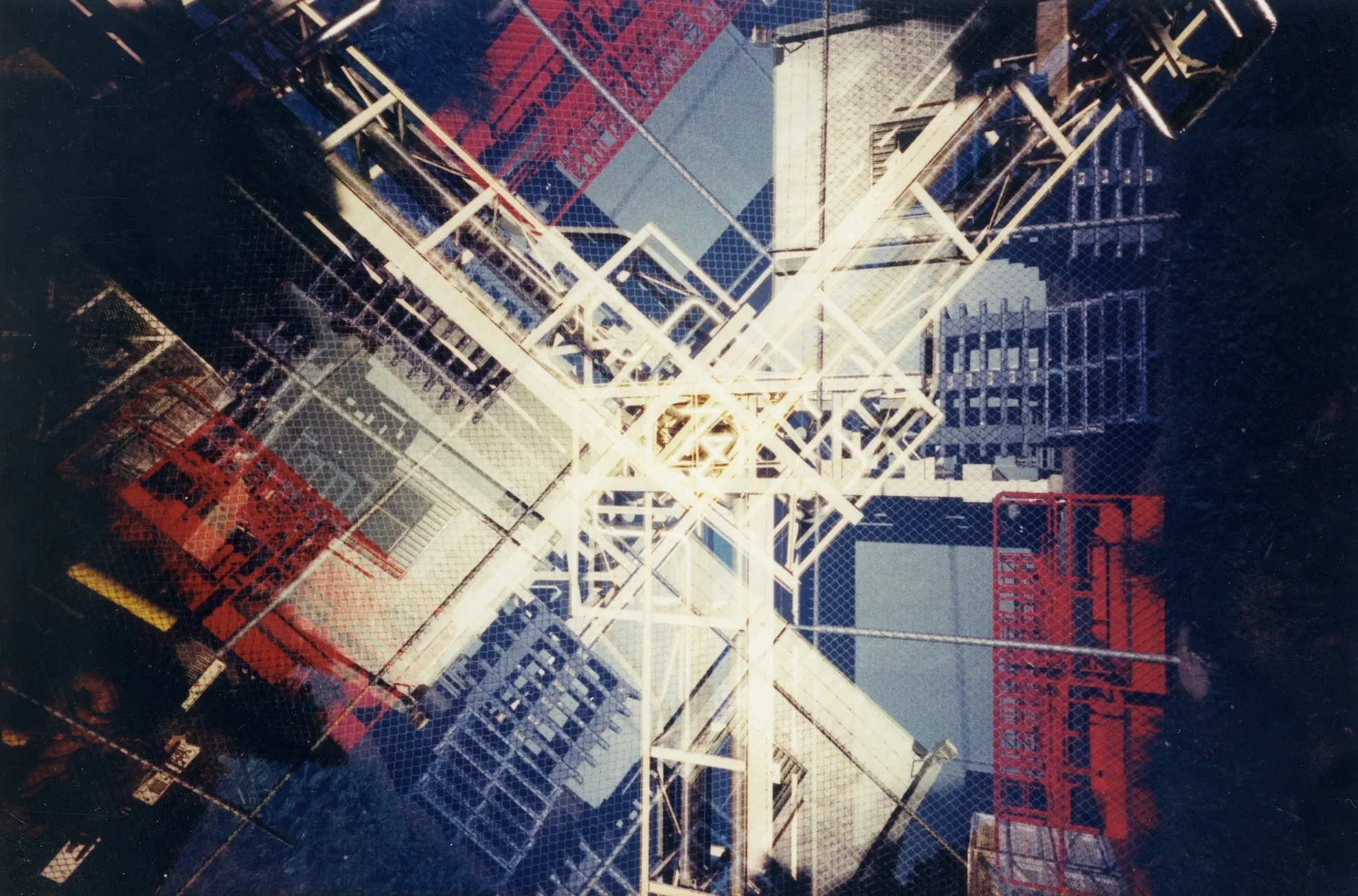 Blurred, abstract long-exposure photograph of a radial metal structure with white, red, and blue tones.